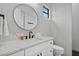 Modern bathroom features a round mirror, white countertop, and a textured white accent wall at 14166 Fort Worth Cir, Port Charlotte, FL 33981