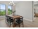Modern dining room with a wooden table, six chairs, decorative chandelier and a view of the pond at 14166 Fort Worth Cir, Port Charlotte, FL 33981