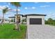 Modern exterior with a dark gray garage door, manicured lawn, and front yard palm trees at 14166 Fort Worth Cir, Port Charlotte, FL 33981