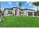 Gorgeous modern home with manicured lawn, palm trees, a dark gray garage door and a light gray brick driveway at 14166 Fort Worth Cir, Port Charlotte, FL 33981