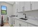Bright laundry room featuring white cabinets, a modern sink, and a high-efficiency washer and dryer at 14166 Fort Worth Cir, Port Charlotte, FL 33981
