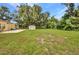 Green backyard with a storage shed and mature trees provides shade and privacy at 1478 Harmony Dr, Port Charlotte, FL 33952