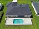 Aerial view of backyard with a sparkling pool, gray brick patio, fenced in yard and dark shingle roof at 15741 Autry Cir, Port Charlotte, FL 33981