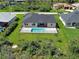 An aerial view of the home shows a lush green lawn, mature landscaping, and a private backyard swimming pool at 15741 Autry Cir, Port Charlotte, FL 33981