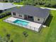 The private backyard features a screened-in lanai, heated pool, lush green grass, and mature landscaping at 15741 Autry Cir, Port Charlotte, FL 33981