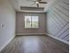 Bright bedroom featuring wood-look tile flooring, decorative accent wall, a ceiling fan and a view from the window at 15741 Autry Cir, Port Charlotte, FL 33981