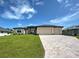 Charming single-story home with a three-car garage, beautiful stone accents, and a well-manicured lawn at 15741 Autry Cir, Port Charlotte, FL 33981