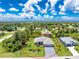Expansive aerial view of a well-maintained home showcasing a lush lawn and a neighborhood surrounded by mature trees at 185 Hercules Dr, Rotonda West, FL 33947