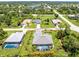 An aerial view of a single-Gathering home featuring a screened-in pool, a neatly manicured lawn, and mature trees at 185 Hercules Dr, Rotonda West, FL 33947
