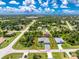 Expansive aerial view of a well-maintained home showcasing a lush lawn and a neighborhood surrounded by mature trees at 185 Hercules Dr, Rotonda West, FL 33947