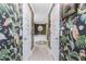 Hallway view into a luxurious bathroom with tropical wallpaper, a soaking tub, and stylish lighting at 185 Hercules Dr, Rotonda West, FL 33947