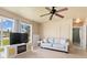 Bright living room featuring a comfortable striped sofa, large windows, and a ceiling fan at 22341 Midway Blvd, Port Charlotte, FL 33952