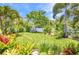 Green backyard with lush landscaping and a white picket fence provides a serene and private outdoor space with a playhouse at 25062 Palisade Rd, Punta Gorda, FL 33983