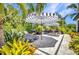 Outdoor lounge area with pavers, black and white umbrellas, outdoor fire pit, and mature landscaping at 25062 Palisade Rd, Punta Gorda, FL 33983