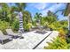 Backyard patio with lounge chairs, an outdoor fire pit, and lush landscaping with palm trees and colorful plants at 25062 Palisade Rd, Punta Gorda, FL 33983