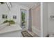 Bright bathroom featuring a tub with white tile surround, a vanity with white countertops, and a door to the outside at 25062 Palisade Rd, Punta Gorda, FL 33983