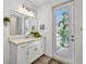 Bathroom vanity with white cabinets, quartz countertops, a decorative mirror, and a door that leads to an outdoor space at 25062 Palisade Rd, Punta Gorda, FL 33983