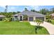 Charming single-story home with lush green lawn, well-maintained landscaping, and a convenient three-car garage at 25062 Palisade Rd, Punta Gorda, FL 33983