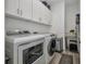 Laundry room featuring a washer and dryer, overhead cabinets, and a storage area for laundry supplies at 25062 Palisade Rd, Punta Gorda, FL 33983