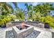 Cozy patio area with built-in seating around a modern fire pit and lush tropical landscaping for a relaxing outdoor retreat at 25062 Palisade Rd, Punta Gorda, FL 33983