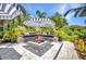 Beautiful outdoor patio features a fire pit, built-in seating, striped umbrellas and lush landscaping for relaxing and entertaining at 25062 Palisade Rd, Punta Gorda, FL 33983