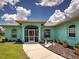 Inviting turquoise home exterior featuring a screened entry, well-manicured lawn and landscaping with potted plants at 2969 Wells Ave, North Port, FL 34286