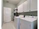 A laundry room with a washer and dryer, and white storage cabinets at 2969 Wells Ave, North Port, FL 34286
