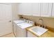 Convenient laundry area with white machines, sink and storage for laundry supplies at 421 Marsh Creek Rd, Venice, FL 34292