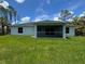 View of the home's back exterior, featuring a covered patio and lush green lawn at 8530 Sawyer Cir, North Port, FL 34288