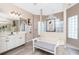 Bright bathroom with a glass block window, a double vanity, wood floors, and a separate walk-in shower at 9954 Audrey St, Port Charlotte, FL 33981