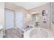 Bright bathroom with a large tub, a marble countertop vanity, wood floors, and a separate seating bench at 9954 Audrey St, Port Charlotte, FL 33981