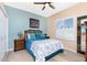 A comfortable bedroom featuring a ceiling fan, blue walls, and a bright window at 9954 Audrey St, Port Charlotte, FL 33981