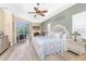 Bright main bedroom featuring tray ceilings, a ceiling fan, wood floors, and private access to outdoor seating at 9954 Audrey St, Port Charlotte, FL 33981