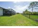Well-manicured backyard with a black metal fence and screened in lanai with hot tub and outdoor seating at 11383 Burgundy Dr, Venice, FL 34293