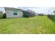 Spacious backyard with lush green grass, black metal fence, and screened in lanai with a hot tub at 11383 Burgundy Dr, Venice, FL 34293