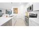 Modern kitchen with stainless steel appliances, white cabinets, and quartz countertops overlooking the living area at 11383 Burgundy Dr, Venice, FL 34293
