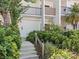 Condo exterior showing a verdant ground floor entry with mature landscaping and concrete stairs at 1144 Bird Bay Way # 102, Venice, FL 34285