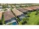 An aerial view of homes with brown roofs and screened-in pools surrounded by lush green grass at 13935 Campoleone St, Venice, FL 34293