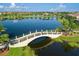 A scenic aerial view of a lake, neighborhood homes, and a bridge surrounded by palm trees and grass at 13935 Campoleone St, Venice, FL 34293