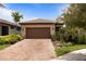 Charming single Gathering home featuring a tile roof, brick driveway, and lush landscaping at 13935 Campoleone St, Venice, FL 34293