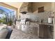 Outdoor kitchen featuring stainless steel appliances, a built-in grill, and tile backsplash at 13935 Campoleone St, Venice, FL 34293
