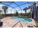 A beautiful screened-in pool area with a brick patio, palm trees, and clear blue skies above the community at 13935 Campoleone St, Venice, FL 34293