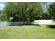 Green backyard with mature trees, white picket fence and white privacy fence at 15037 Mcgraw Ave, Port Charlotte, FL 33953