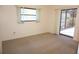 Bedroom featuring carpet, neutral walls, windows, and backyard access at 15037 Mcgraw Ave, Port Charlotte, FL 33953