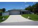 Charming single-story home featuring a well-manicured lawn, a two car garage, and long driveway at 15037 Mcgraw Ave, Port Charlotte, FL 33953