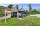 Image shows the screened in back porch of the house with views of the green yard and fence at 1546 Gourmet Rd, North Port, FL 34288