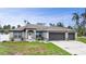 Inviting one-story home showcasing a well-maintained lawn, manicured shrubs, and three-car garage at 1546 Gourmet Rd, North Port, FL 34288