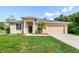 Inviting single-story home with a well-manicured lawn and a two-car garage in a sunny, tropical setting at 1693 Jagust Rd, North Port, FL 34288