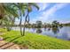 Backyard featuring lush green lawn, mature palm trees, and tranquil lake views at 17188 Cape Horn Blvd, Punta Gorda, FL 33955