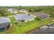 An aerial view of a one-story home with a well-manicured lawn and screened-in lanai, backing onto a canal at 17200 Gulfspray Cir, Port Charlotte, FL 33948